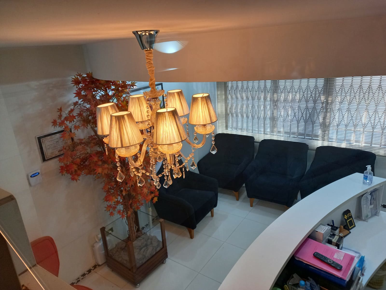 Sala de espera do consultório vista do alto, com lustre, poltronas e recepção
