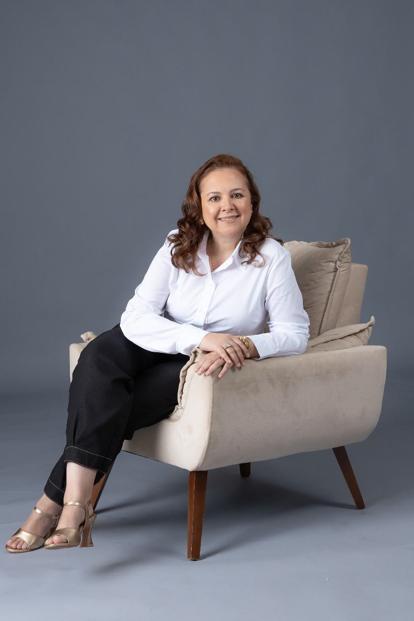 Dra. Rosângela Muniz Soares, cirurgiã-dentista, de camisa branca, sentada em uma poltrona clara